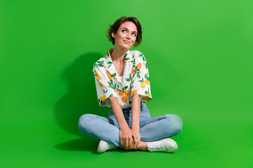Full body photo of young woman sitting floor looking thoughtful wondered spend money on black friday isolated over green color background