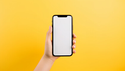 Fototapeta na wymiar hand holding mobile phone on bright solid yellow background with copy space