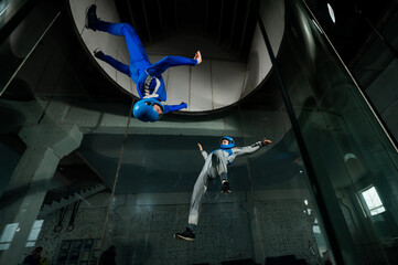 A man and a woman enjoy flying together in a wind tunnel. Free fall simulator - obrazy, fototapety, plakaty