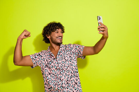 Photo portrait of handsome young guy take selfie flex muscle dressed stylish pink leopard print outfit isolated on yellow color background
