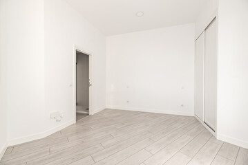 A room with irregular walls with a built-in wardrobe with white sliding doors