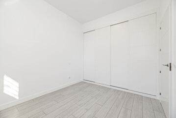An empty room with built-in wardrobes with white sliding doors