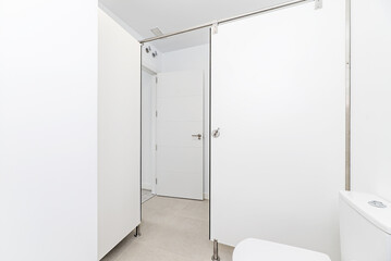 A spacious bathroom with a white-walled shower cubicle with an industrial-style screen, stoneware floors and a white porcelain sink in the corner