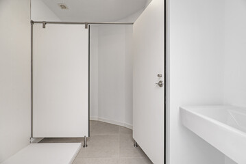 A bathroom with a white-walled shower cubicle with an industrial-style screen and a white porcelain...