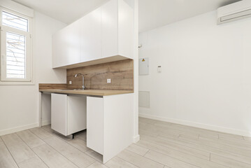 Fototapeta na wymiar Image of a newly installed small kitchen with white furniture with backsplash and countertop of the same material