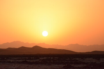 Sunrise at a desert landscape, surrounded by sand and arid vegetation
