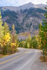 Fototapeta na wymiar Vertical of a winding highway surrounded by mountain ranges and autumn trees