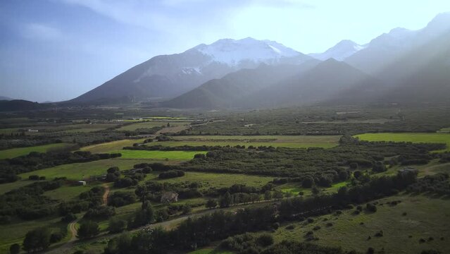 Drone footage of the green fields with mountains under blue dusk sky in the background, Greece