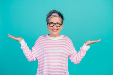 Photo of cheerful funky lady wear striped sweater spectacles comparing arms empty space isolated...
