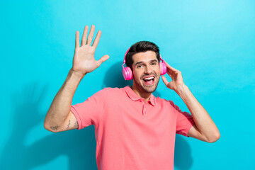 Photo of trendy dj meloman guy in pink earphones raised palm up enjoying lofi music playlist...