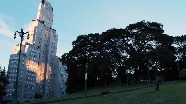A Man Walking His Dog at San Martin Square with the famous Kavanagh Building in Background, Buenos Aires, Argentina.  