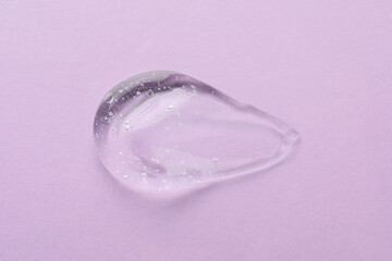 Clear cosmetic gel on light violet background, top view