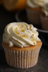Delicious cupcake with white cream and lemon zest on table, closeup