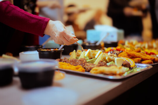 Hands Taking Food from a Table at a Swedish Buffet Party. People enjoying different snacks at a festive gathering
