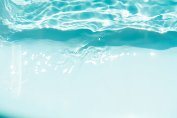 Bluewater waves on the surface ripples blurred. Defocus blurred transparent blue colored clear calm water surface texture with splash and bubbles. Water waves with shining pattern texture background.
