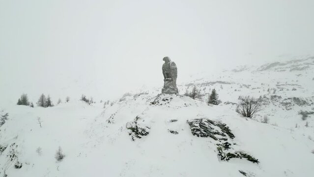 Heavy snow in the mountains. A stone statue depicting an eagle. Winter in the mountains. Simplon Pass
