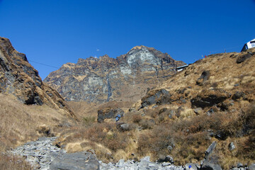 Stunning views of snow mountains, blue skies and large rocks along the track to Annapurna Base Camp.