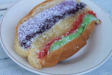 Torn bread topped with colorful jam and a sprinkling of grated coconut in a plate on the table