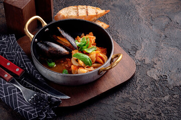 Italian Tuscan tomato soup with seafood. Cooking soup with mussels, shrimps, squid and basil, copy...