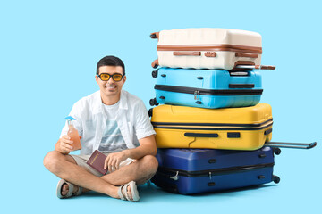 Male tourist with suitcases, passport and lemonade on blue background - obrazy, fototapety, plakaty