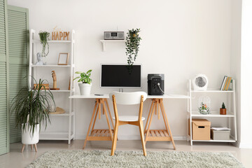 Comfortable workspace with modern computer and portable power station in contemporary room