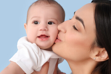 Happy mother with her little baby on blue background, closeup