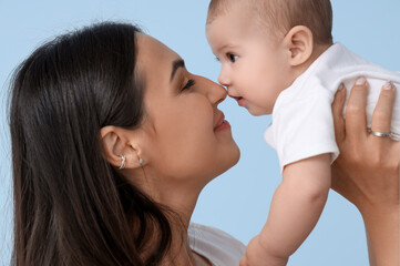 Happy mother with her little baby on blue background, closeup