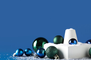 Decorative stands with different Christmas balls and snow on blue background