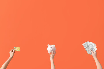 Women with credit card, piggy bank and dollar banknotes on orange background