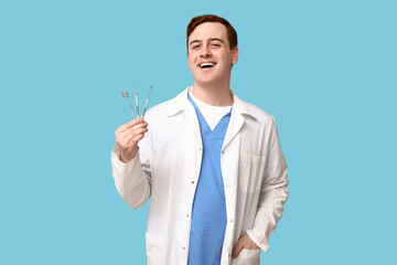 Male dentist with dental tools on blue background. World Dentist Day