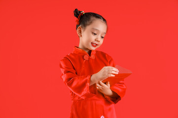 Cute little Asian girl with envelope on red background. Chinese New Year celebration