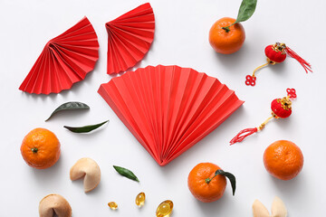 Composition with paper fans, tangerines and Chinese symbols on white background. New Year...