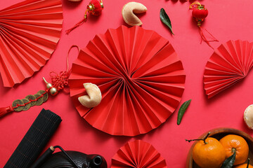 Composition with paper fans, tangerines and Chinese symbols on red background. New Year celebration