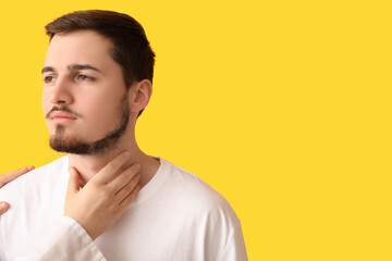 Endocrinologist examining thyroid gland of young man on yellow background