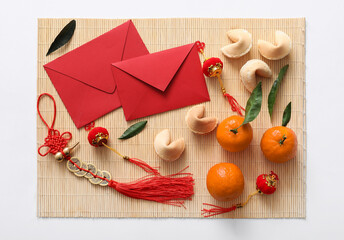 Bamboo mat with tangerines, envelopes, fortune cookies and Chinese symbols on white background. New...