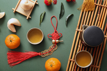 Composition with tangerines, tea set and Chinese symbols on green background. New Year celebration