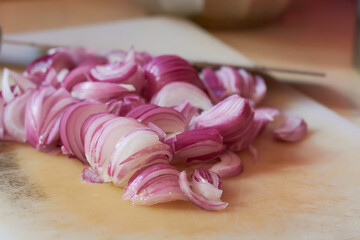 close-up of chopped or sliced red onion on cutting board, fresh flavored vegetable ingredient for...