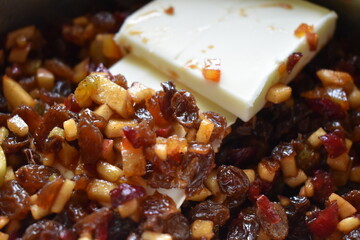 Adding butter to cooking mincemeat. a mix of small pieces of dried fruit, fresh apples, and orange...