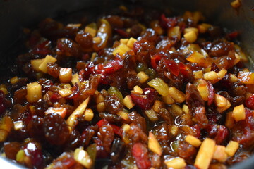A bowl containing a cooked mix of small pieces of dried fruit, fresh apples, and orange peel, spices, sugar and brandy.