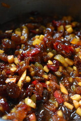 A bowl containing a cooked mix of small pieces of dried fruit, fresh apples, and orange peel, spices, sugar and brandy. vertical photo.