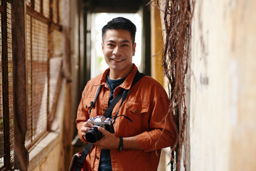 Portrait of smiling photographer with digital camera waiting for client - obrazy, fototapety, plakaty