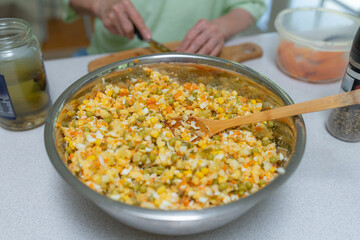 Old lady making a vegetable food in metal bowl. Cutting veggies for salad.