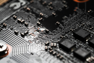 Black printed circuit board with microchips and capacitors, macro photo
