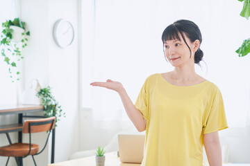 手で案内する自宅で仕事をする女性　立ちポーズ