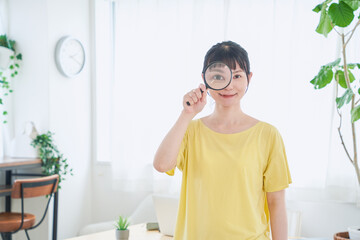 虫眼鏡を持つ自宅で仕事をする女性　立ちポーズ