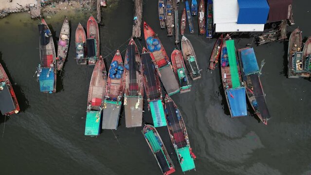 Drone footage above fishermen boats along a small river in Kampot province, Cambodia. Camera slide from left to right showing the little harbour 1-3