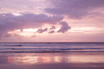 Obraz premium Beautiful peach sunset over the ocean and purple clouds.