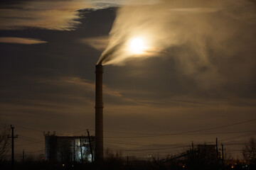 smoke coming from the coal power plant in the night. The full moon and the smoke of the thermal plant.