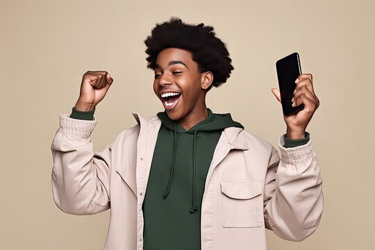 Happy African American Teenager Ethnic Cool Guy Student Winner Holding Cell Phone Winning Money Online Cellphone Using Mobile App Celebrating Gre Result Yes Isolated Beige Background