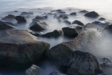 A long exposure of misty sea and rocks, selective focus. Nature composition. A slow shutter speed was used to see the movement